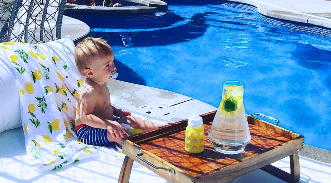 baby boy sitting by the pool with kloud bambu lemon print bamboo hooded bath towel behind