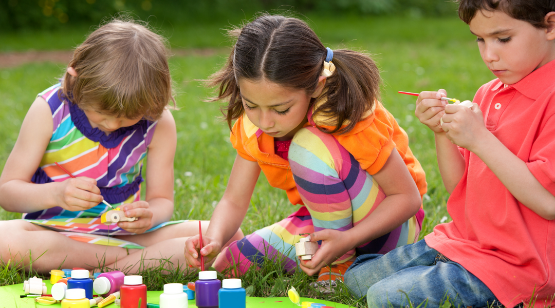 kids sitting on the playground while doing art-related summer activities